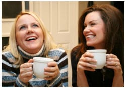 Two women laughing and drinking coffee