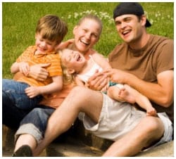 Family of four sitting in the grass posing for a picture