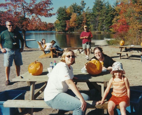 Old photo of family on the beach, carving pumpkins at a picnic table.