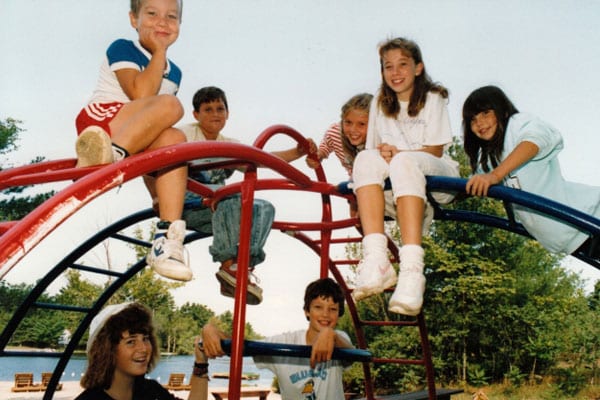 Old photo of several young people on a playground climbing set.