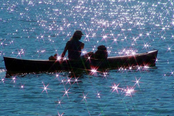 People in a canoe on sparkling waters.