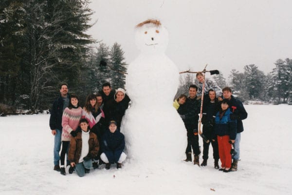 Group posing with a tall snowman.