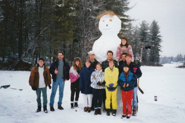 Group posing with a tall snowman.