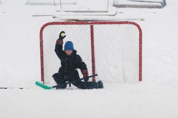 Goalie catching a ball on outdoor ice rink.