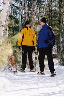 Couple snowshoeing on forest trail.