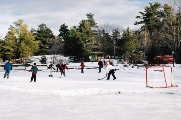 Group playing friendly hockey game on outdoor ice rink.