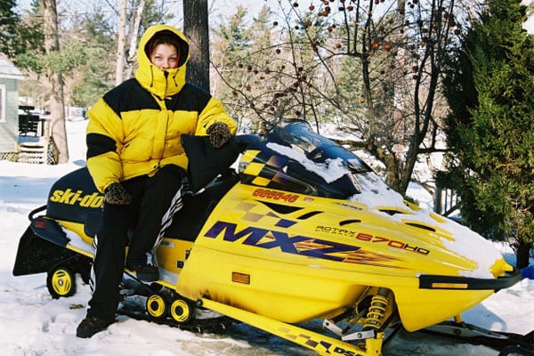 Woman on yellow snowmobile.