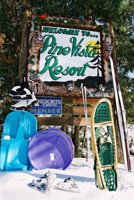 Pine Vista sign, skis, snowshoes, and sleds.