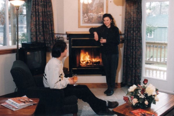 Man and woman sitting by a fireplace.