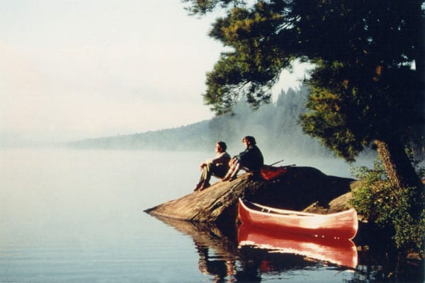 Two people sitting on Stoney Lake shore.