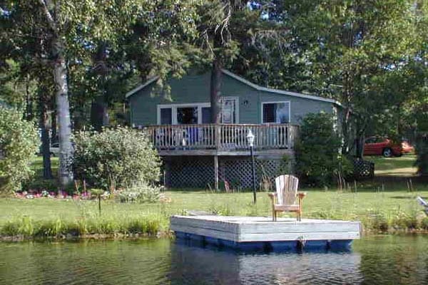 Adirondack chair on a dock behind a vacation home.