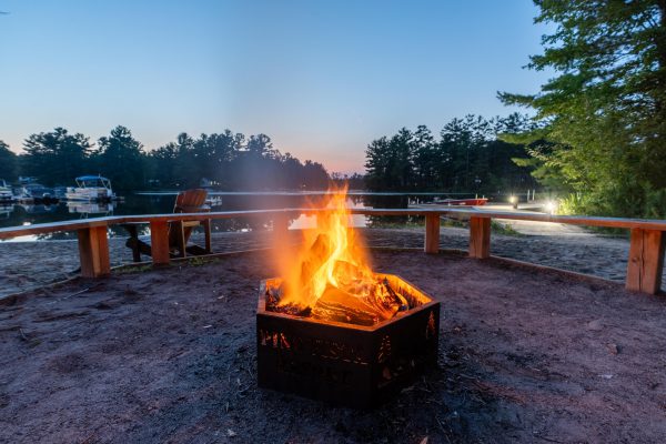 A cozy fire pit on the beach, glowing warmly against the dusky sky as the sun sets on the horizon.