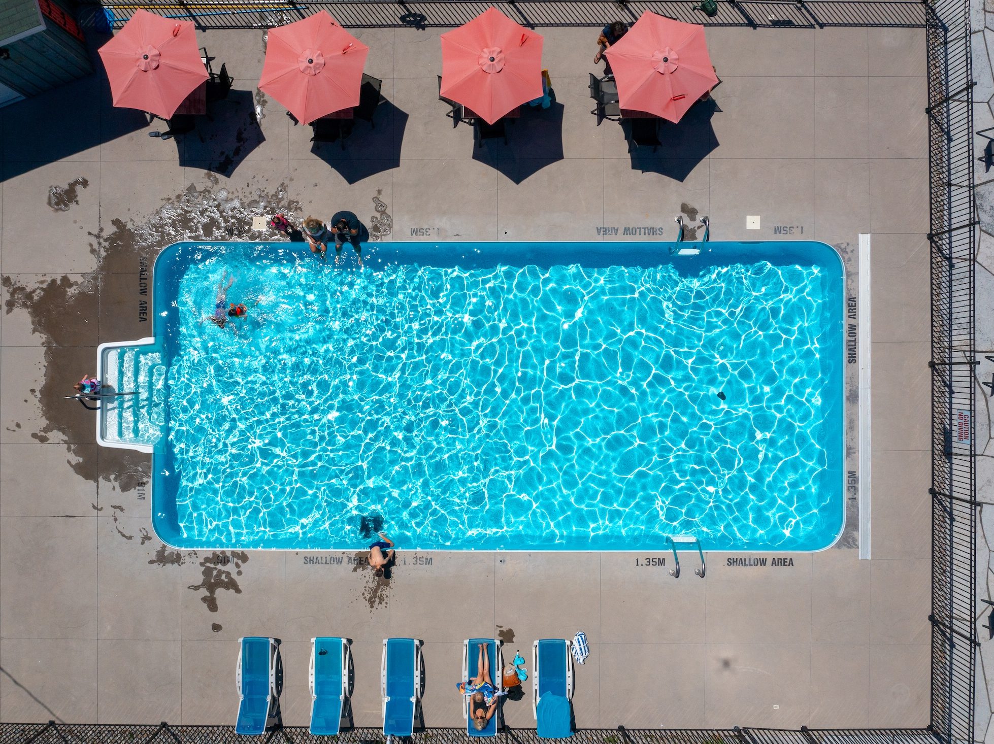 Pine_Vista_June2026_Adams_DJI_0964 Aerial view of swimming pool, with red umbrellas lined up along its edge